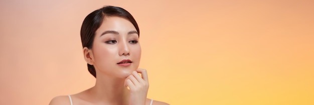 Beautiful Young Asian Woman Looking While Touching Chin feeling so happy and cheerful with healthy Clean and Fresh skin