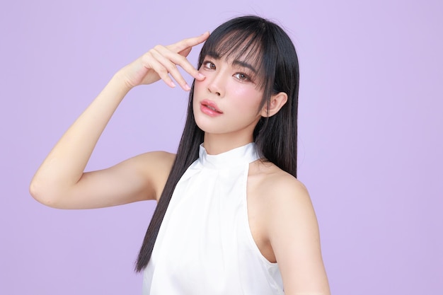 Beautiful young Asian woman model long hair with natural makeup on face clean skin on isolated violet background Cute girl portrait Facial treatment Body care Beauty and Spa