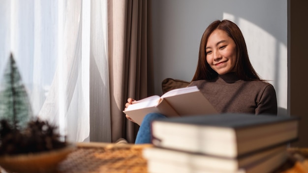 A beautiful young asian woman reading book at home