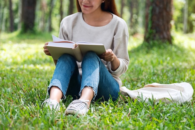 A beautiful young asian woman reading a book while sitting in the park