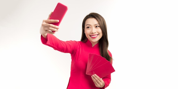 Beautiful young Asian woman in traditional costumes taking selfie at Tet celebration