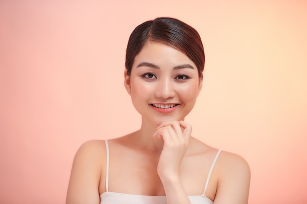 Beautiful young asian woman with clean fresh skin on beige background,