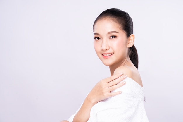 Beautiful Young Asian woman with clean fresh white skin face in beauty pose touching shoulder with finger