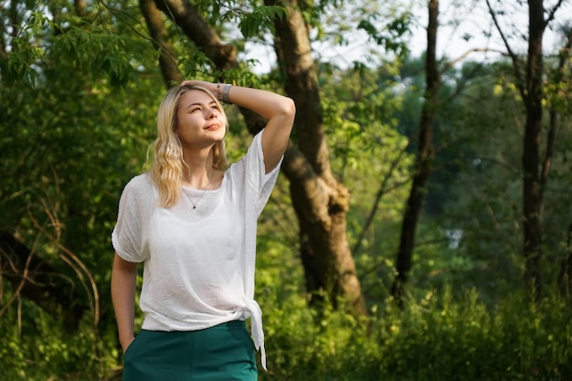 Beautiful young blonde in the forest The girl enjoys nature