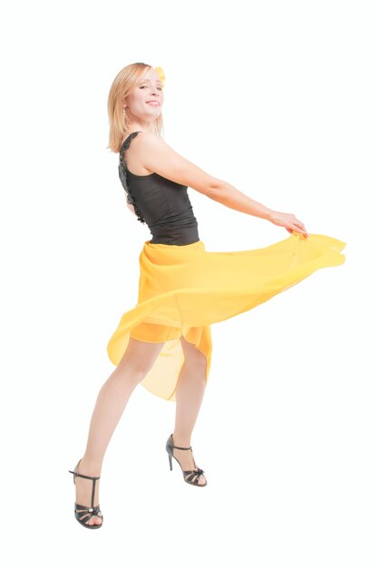 Beautiful young blonde girl in a black top a yellow skirt and black high heel shoes dancing