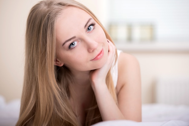 Beautiful young blonde girl lying on a bed in her bedroom