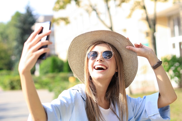 Beautiful young blonde girl using mobile phone while standing outdoors.