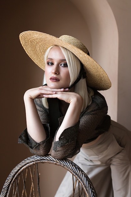 Beautiful young blonde model is posing in straw hat and green transparent blouse