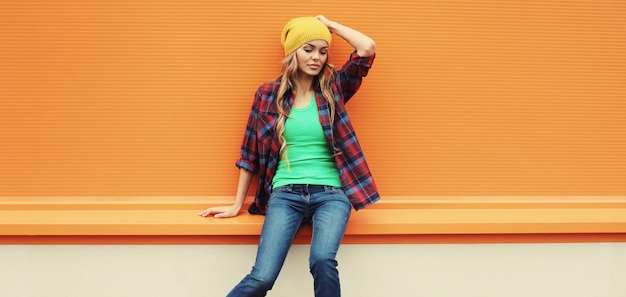 Photo beautiful young blonde woman posing in yellow hat casual shirt on colorful orange background