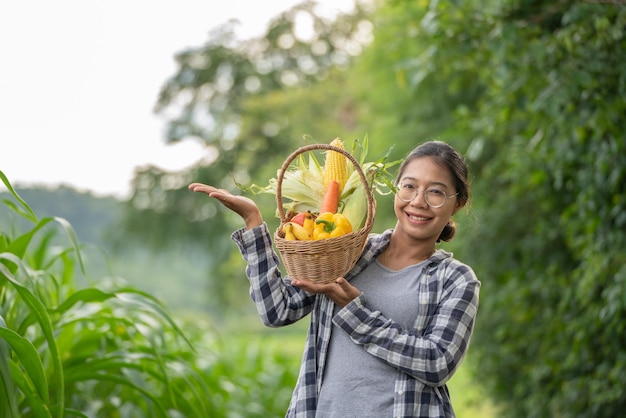 Beautiful young brunette Portrait Famer Woman hand holding Vegetables in the bamboo basket on green