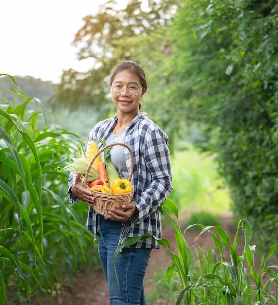 Beautiful young brunette Portrait Famer Woman hand holding Vegetables in the bamboo basket on green