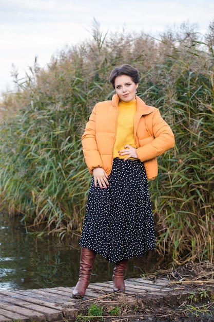 Beautiful young brunette woman posing in a yellow jacket long skirt and boots autumn weather