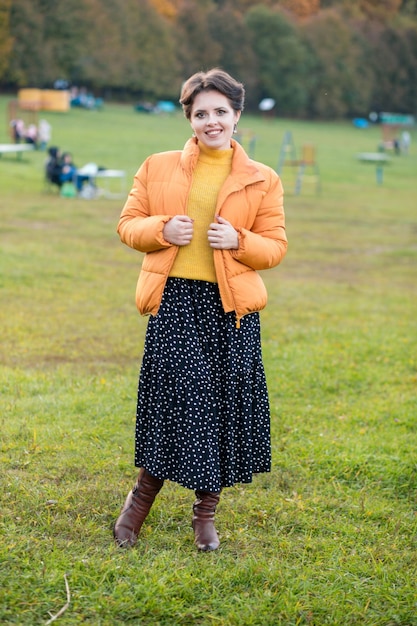 Beautiful young brunette woman posing in a yellow knitted sweater and jacket against the background