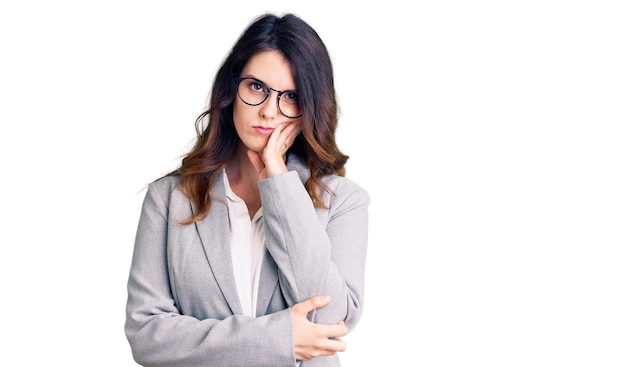 Beautiful young brunette woman wearing business clothes and glasses thinking looking tired and bored with depression problems with crossed arms