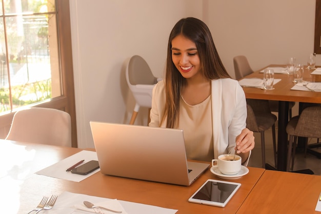 Beautiful young business girl using her laptop in a restaurant