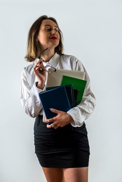 Beautiful young business lady standing with documents isolated on white background