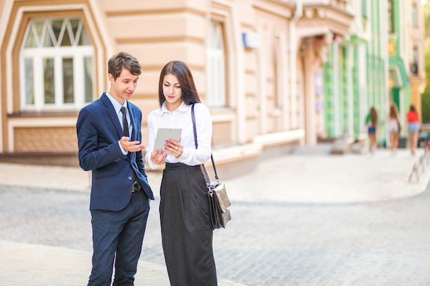 Beautiful young business woman and handsome businessman in formal suits are using a digital tablet