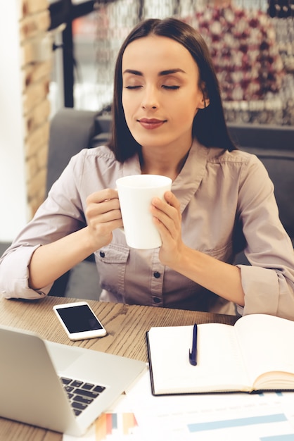 Beautiful young business woman is holding a cup.