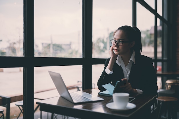 Beautiful young business woman sitting at table and taking notes. In cafe,