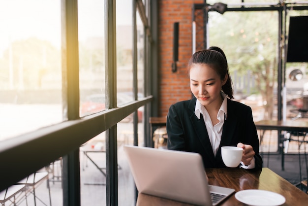 Beautiful young business woman sitting at table and taking notes