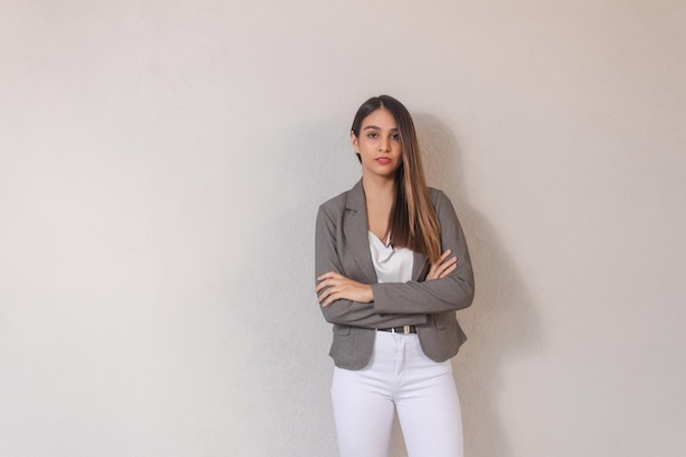 Beautiful young businesswoman with crossed arms on white background