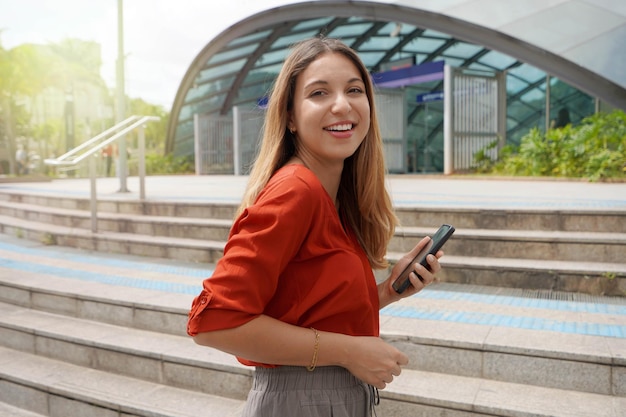 Beautiful young casual woman holding phone climbs stairs to take the metro in Brooklin station Sao Paulo Brazil