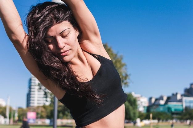 Beautiful young caucasian latin woman outdoors stretching for exercise