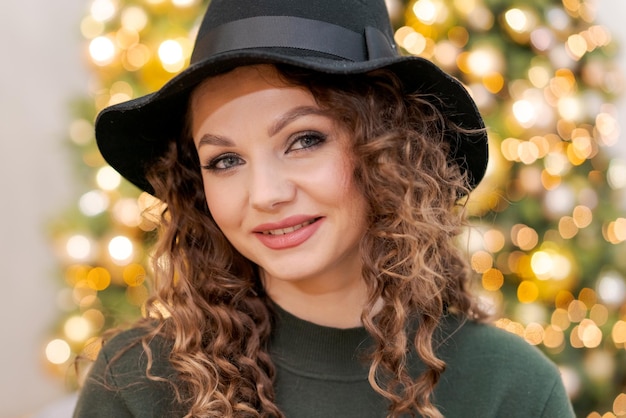 Beautiful young caucasian woman in green sweater and black hat on her head