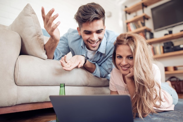 Beautiful young couple in casual clothes is using a laptop