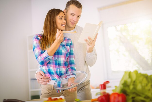 Photo beautiful young couple cooking healthy meal in the domestic kitchen. they reading recipe in the cookbook.