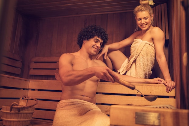 Beautiful young couple enjoying and relaxing in a finnish sauna at the spa centre.