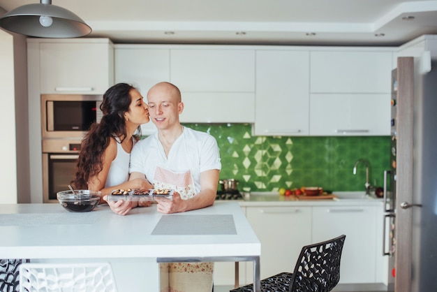 Beautiful young couple graphed smiling  while cooking in the kitchen at home.