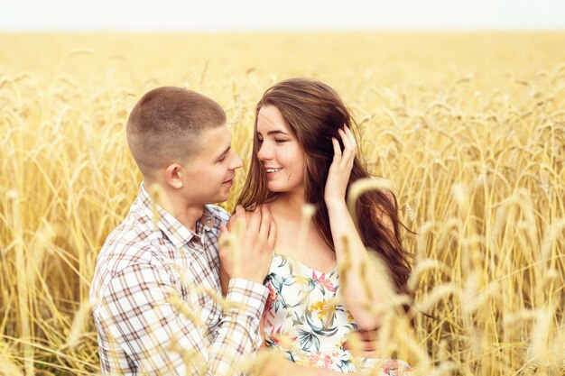 Beautiful young couple is resting on a wheat field