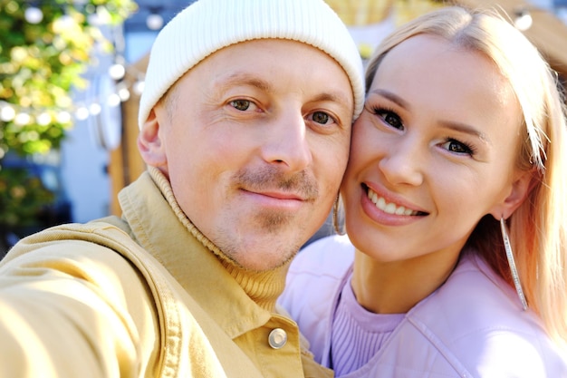 Beautiful young couple looking at the phone camera smiling and taking a selfie