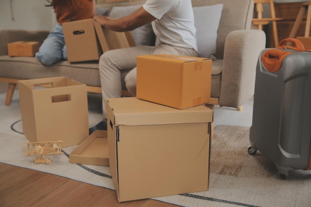 Photo beautiful young couple in love having fun unpacking things from cardboard boxes while moving in together in their new apartment