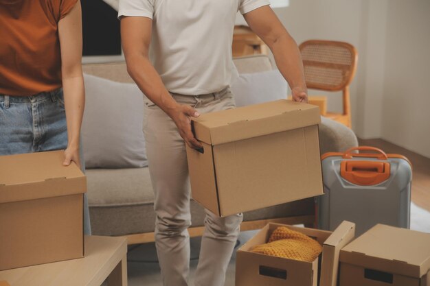 Photo beautiful young couple in love having fun unpacking things from cardboard boxes while moving in together in their new apartment