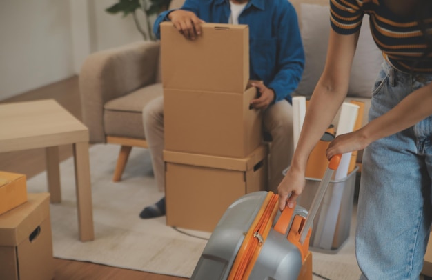 Photo beautiful young couple in love having fun unpacking things from cardboard boxes while moving in together in their new apartment