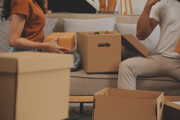 Beautiful young couple in love having fun unpacking things from cardboard boxes while moving in together in their new apartment