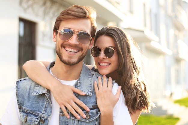 Beautiful young couple in love walking outdoors at the city street, hugging.