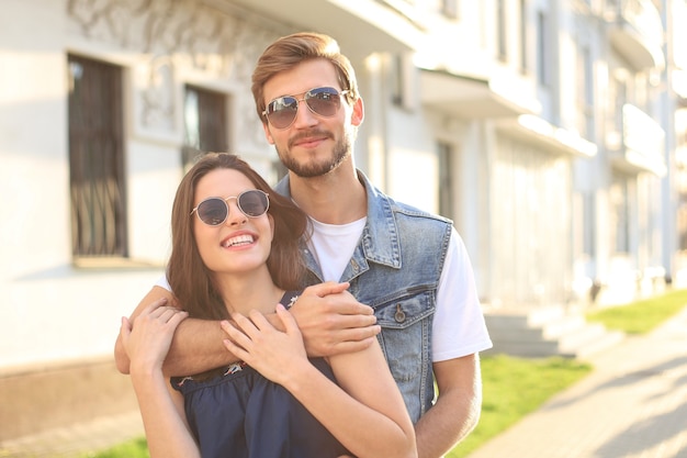 Beautiful young couple in love walking outdoors at the city street, hugging.