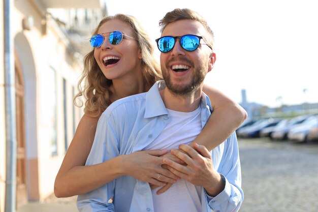 Beautiful young couple in love walking outdoors at the city street, hugging.