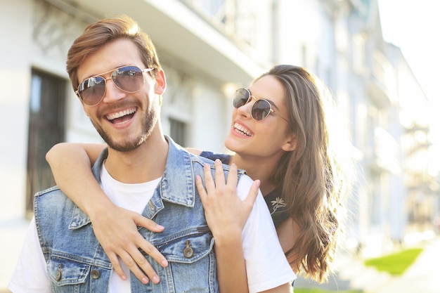 Beautiful young couple in love walking outdoors at the city street, hugging.