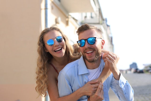 Beautiful young couple in love walking outdoors at the city street, hugging.