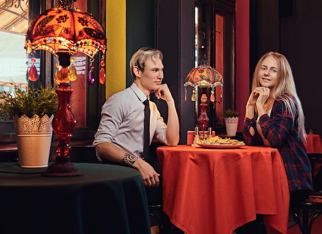 Beautiful young couple ordered nachos during dating at mexican restaurant.