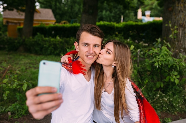 Beautiful young couple relaxing in the park and makes selfie