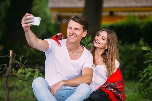 Beautiful young couple relaxing in the park and makes selfie