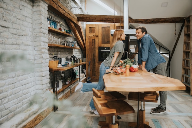 Beautiful young couple smiling while cooking in kitchen at home