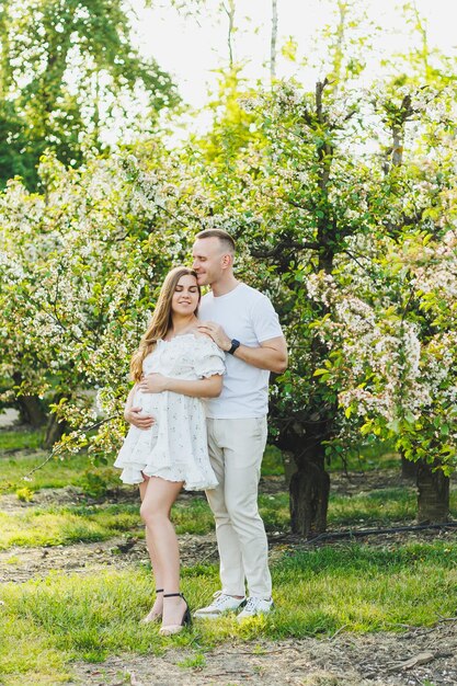 Beautiful young couple in spring garden Beauty lifestyle family concept A happy mother is expecting a baby A happy young couple in a blooming garden