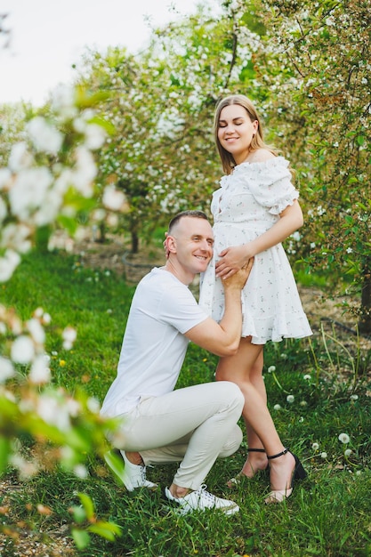 Beautiful young couple in spring garden Beauty lifestyle family concept A happy mother is expecting a baby A happy young couple in a blooming garden