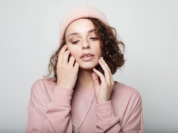 Beautiful young curly woman in headphones listening to music smiling with closed eyes